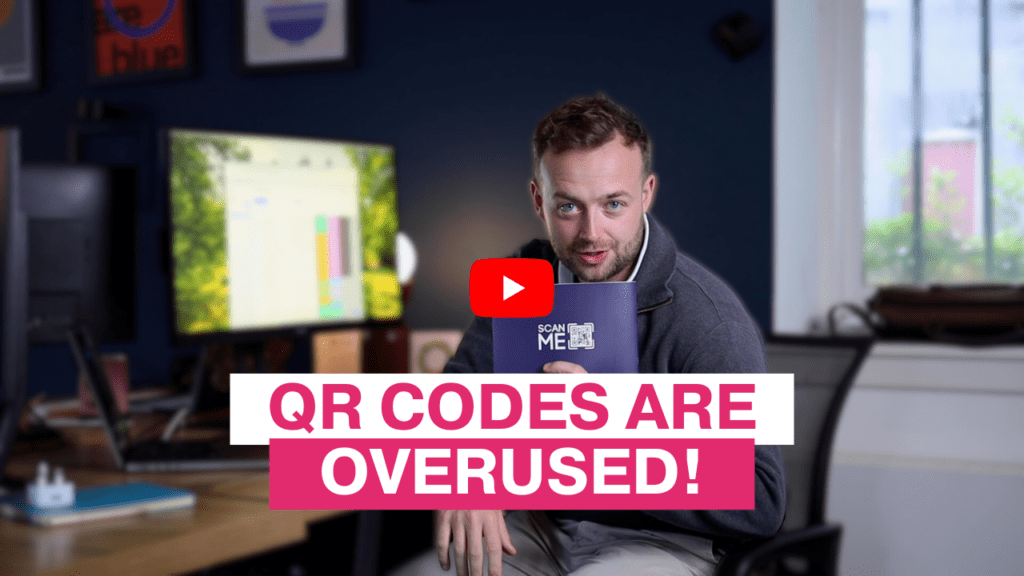 Alex holding a booklet with a QR code at his desk